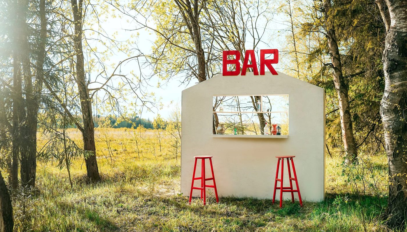 Белый бар с красной вывеской BAR в лесу